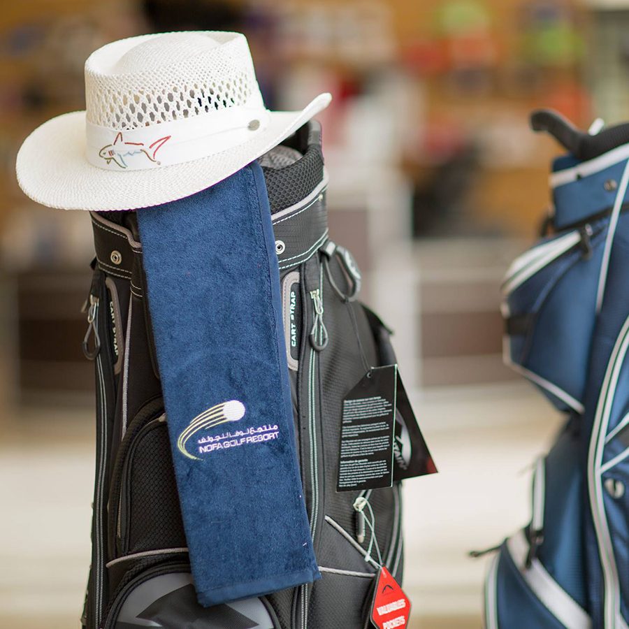 Two golf bags, one of which has a white fedora and a blue towel on it