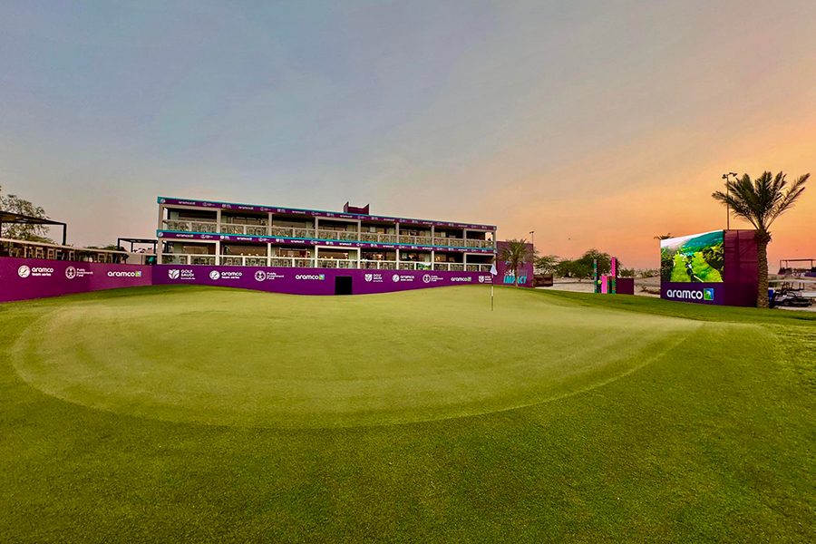 Grass lawn with a purple building and large TV screen at Riyadh Golf Club