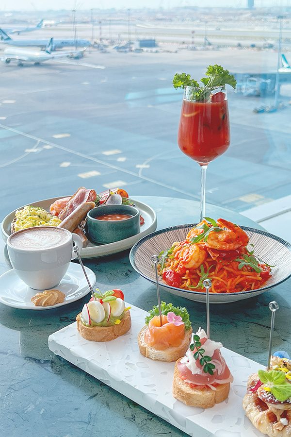 A plate of pinchos, a bowl of prawn and tomato sauce spaghetti, a full English breakfast, a white coffee with a biscuit, and a cocktail served at Intervals Sky Bar & Restaurant, Hong Kong International Airport. 