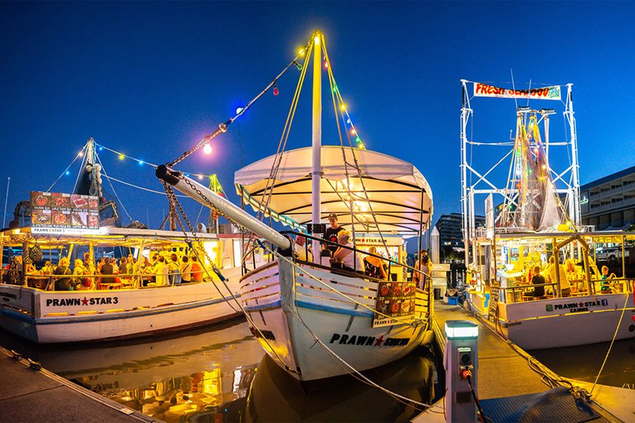 Three white boats with “Prawn Star” painted on the side sit at a dock.
