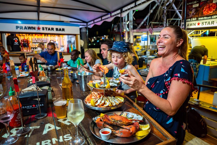 Adults and children seated at Prawn Star, eating seafood platters. 