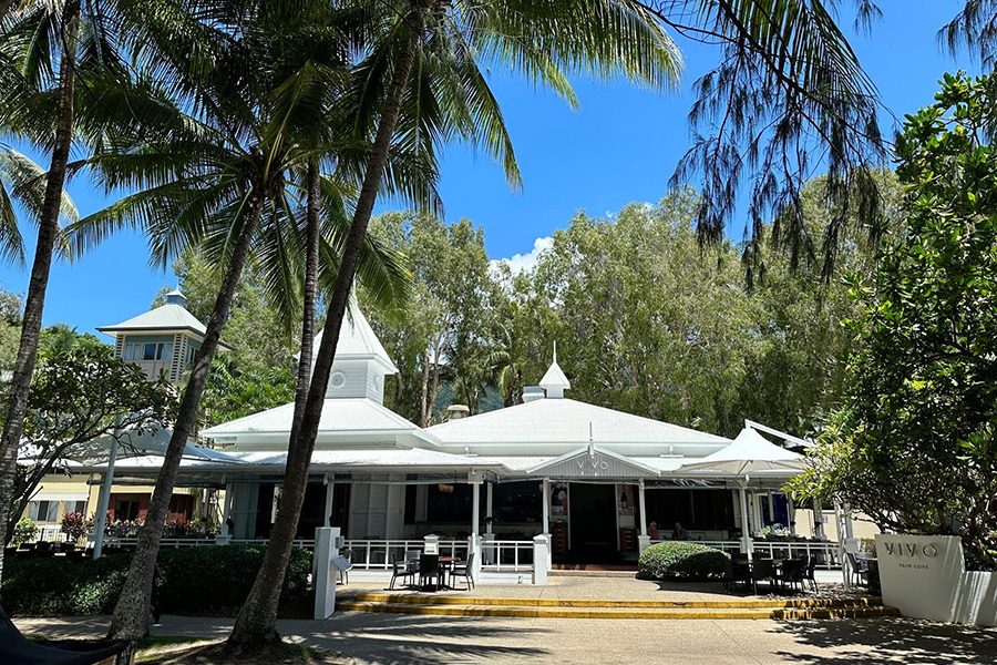 The exterior of Vivo, with a white veranda and many trees. 