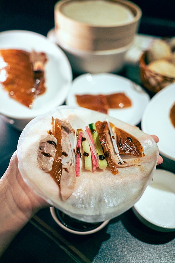 A diner holding a wrap filled with Peking duck and other condiments at Duck De Chine by 1949