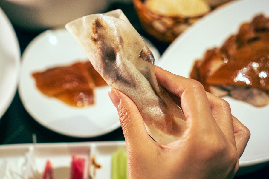 A diner holding a Peking duck wrap at a restaurant