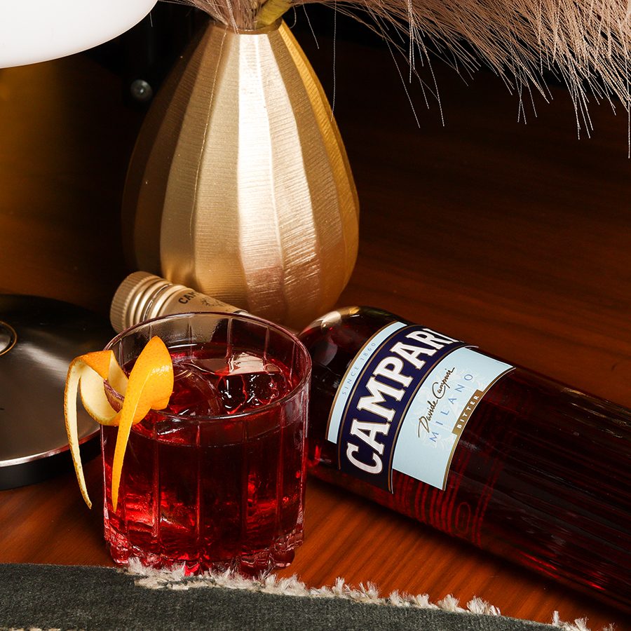 Negroni cocktail lying alongside Campari bottle