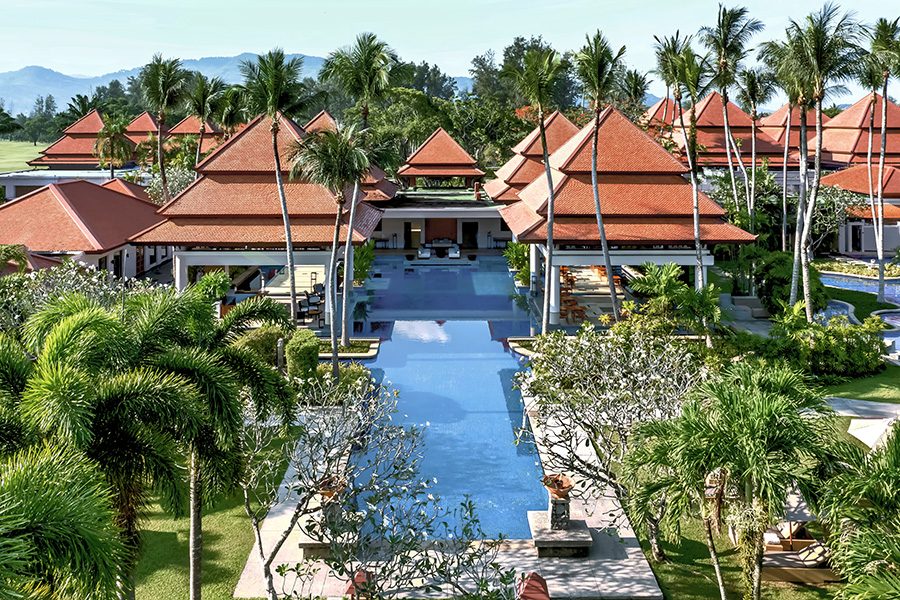 A wide view of Thai-style buildings, palm trees and a swimming pool at Banyan Tree Phuket 