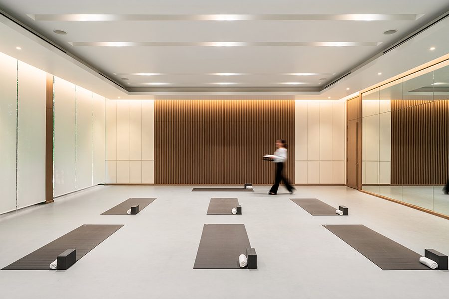 A person crosses a bright, spacious room with yoga mats laid on the floor, at Banyan Tree Phuket 