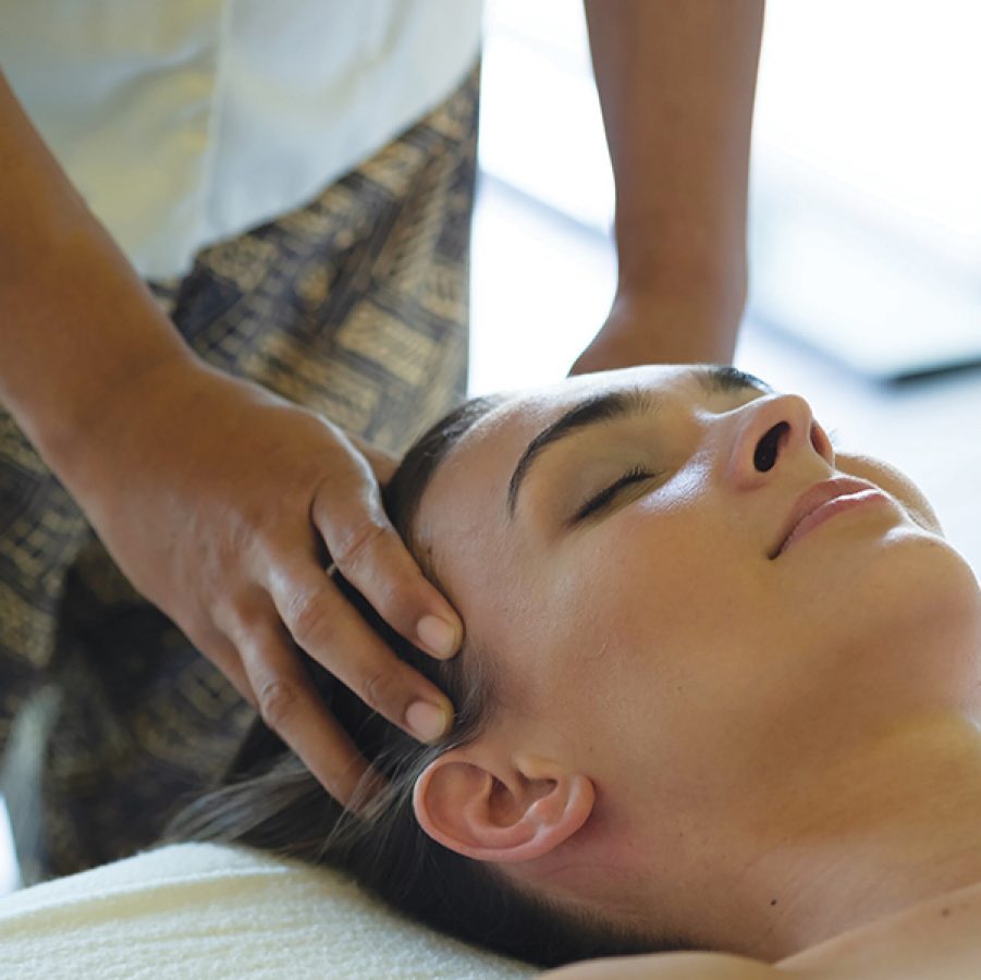A woman lying down receiving a hair treatment and massage