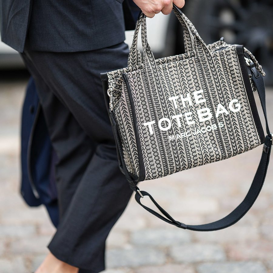 A pedestrian holding Marc Jacobs’ The Tote Bag on the street.