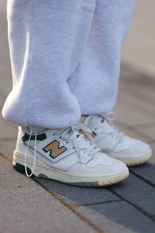 A close-up of someone wearing New Balance trainers on the street. 