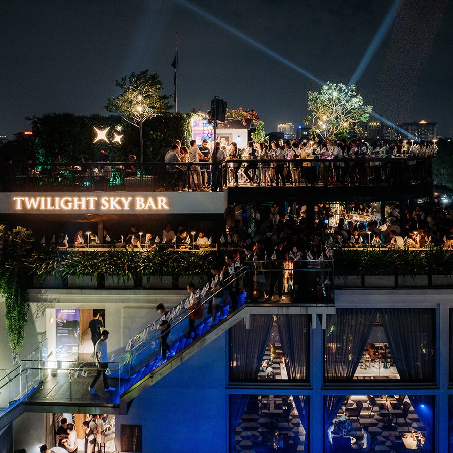 External view of Twilight Sky Bar at night full of people dancing to live music on the rooftop.