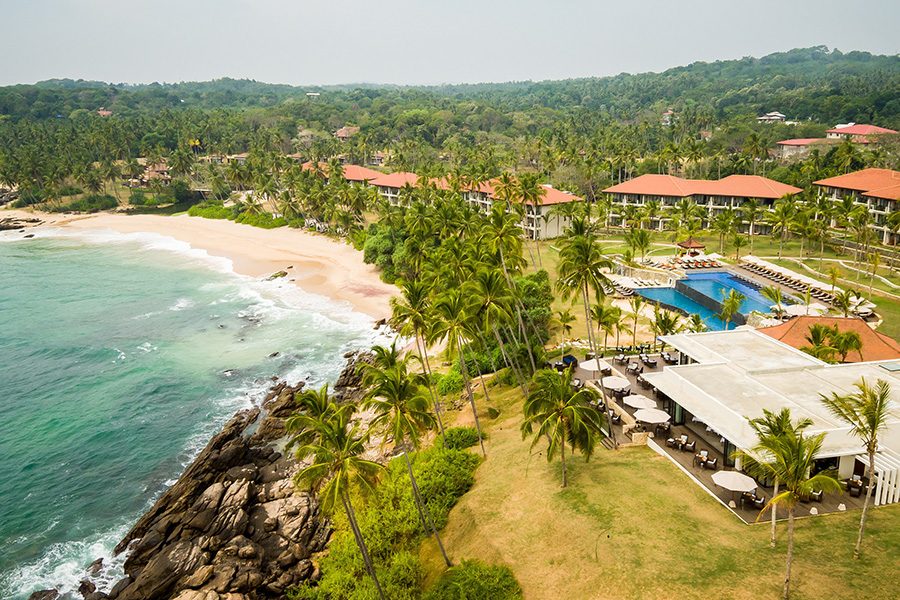 A beach lined with hotels and pools.