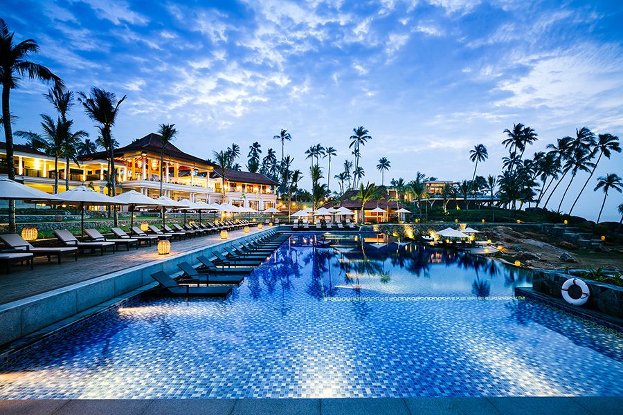A pool with lounge chairs and palm trees.