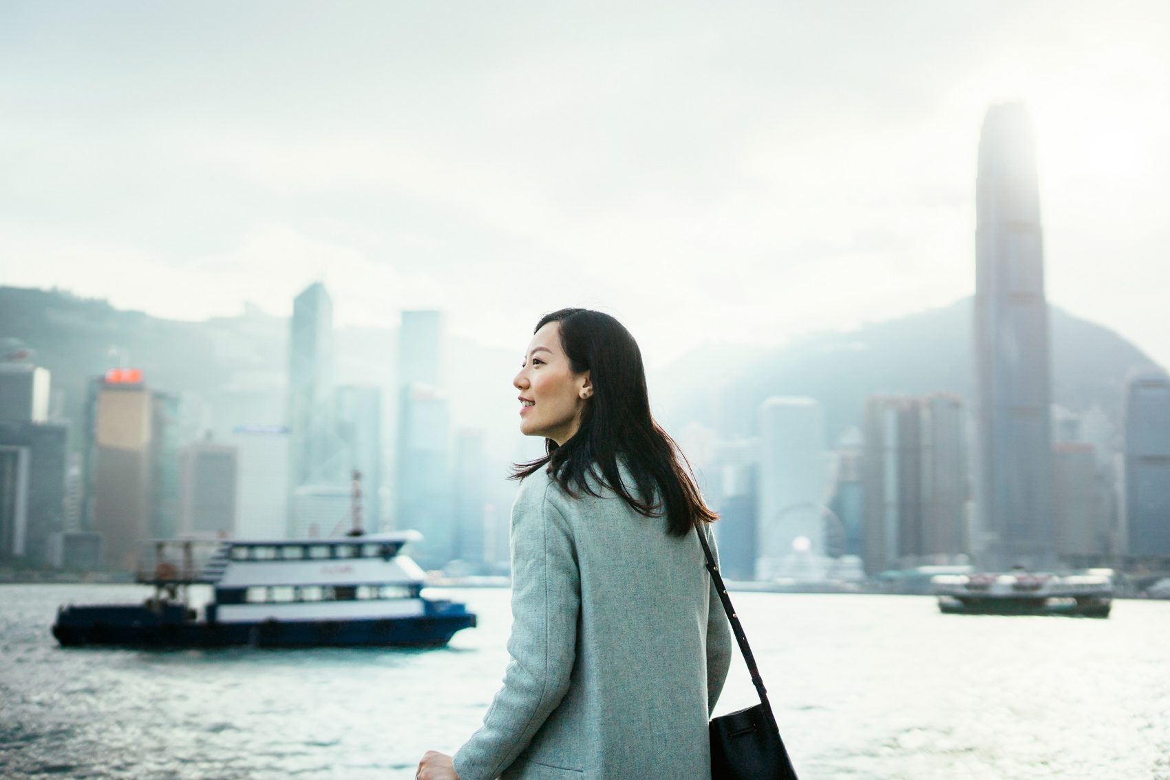 Woman standing against the Hong Kong skyline with the Star Ferry and IFC in the background 