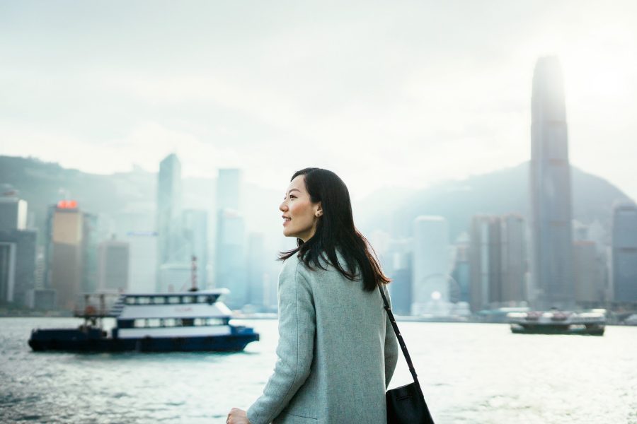 Woman standing against the Hong Kong skyline with the Star Ferry and IFC in the background 