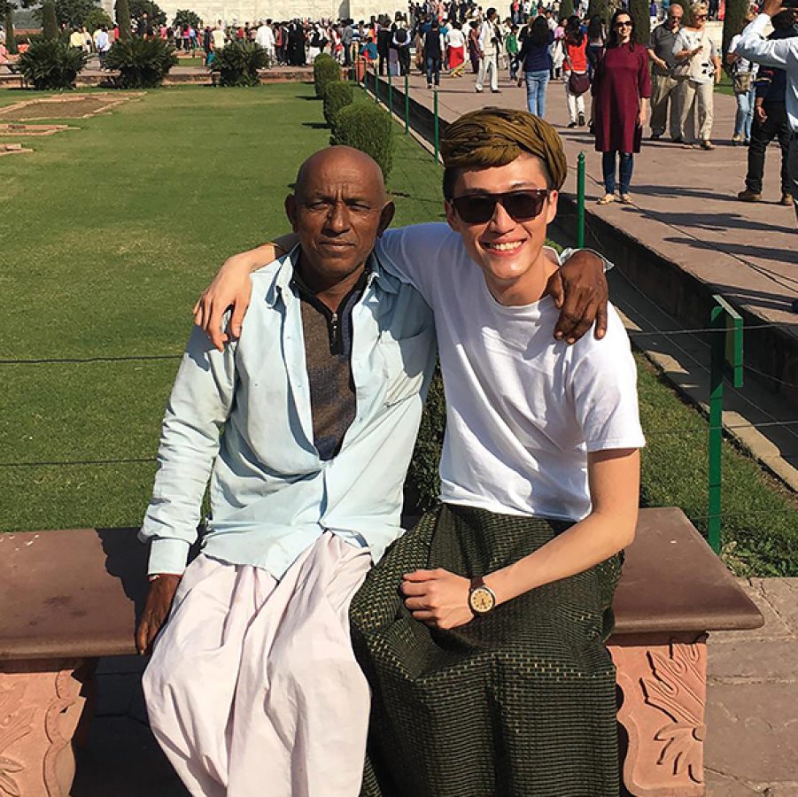 Cathay Flight Purser Eibrab Ho smiles with his arm around an Indian man. They are sitting on a bench outside the Taj Mahal in Delhi.