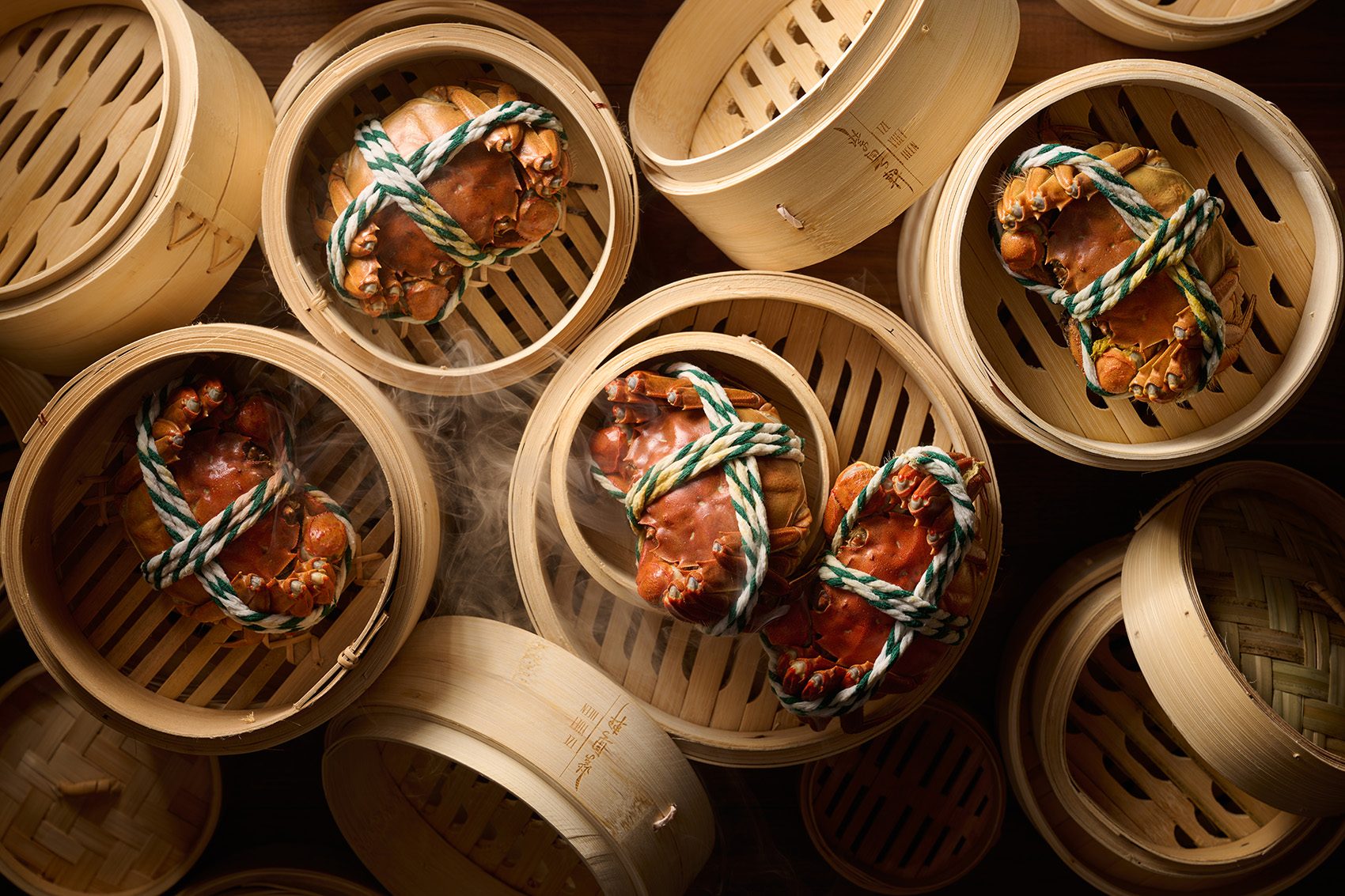 A top-down view of multiple fresh hairy crabs in bamboo steamer baskets served at Tsz Yuet Heen in Tsuen Kwan O, Hong Kong