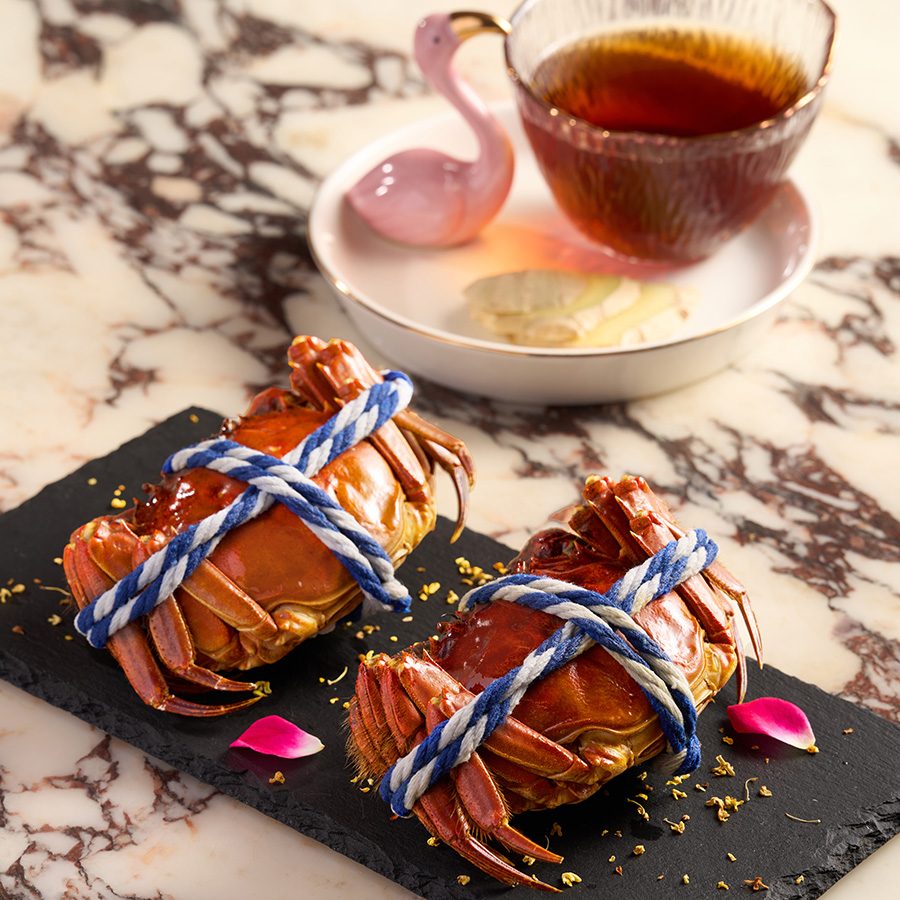 Two steamed hairy crab on a black ceramic plate served with osmanthusa at Voynich in Tsim Sha Tsui, Hong Kong 