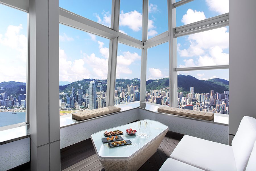  A corner table at Ozone at The Ritz-Carlton Hong Kong with the city skyline in the daytime visible through the windows.