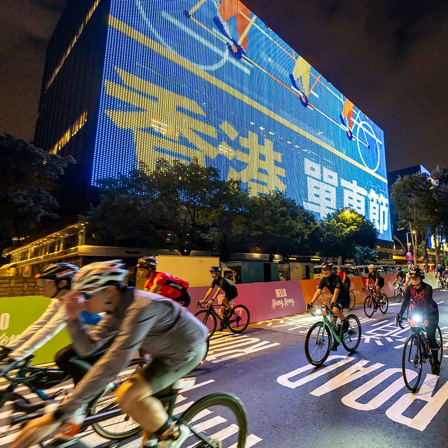 Cyclists ride along a Hong Kong road at night.