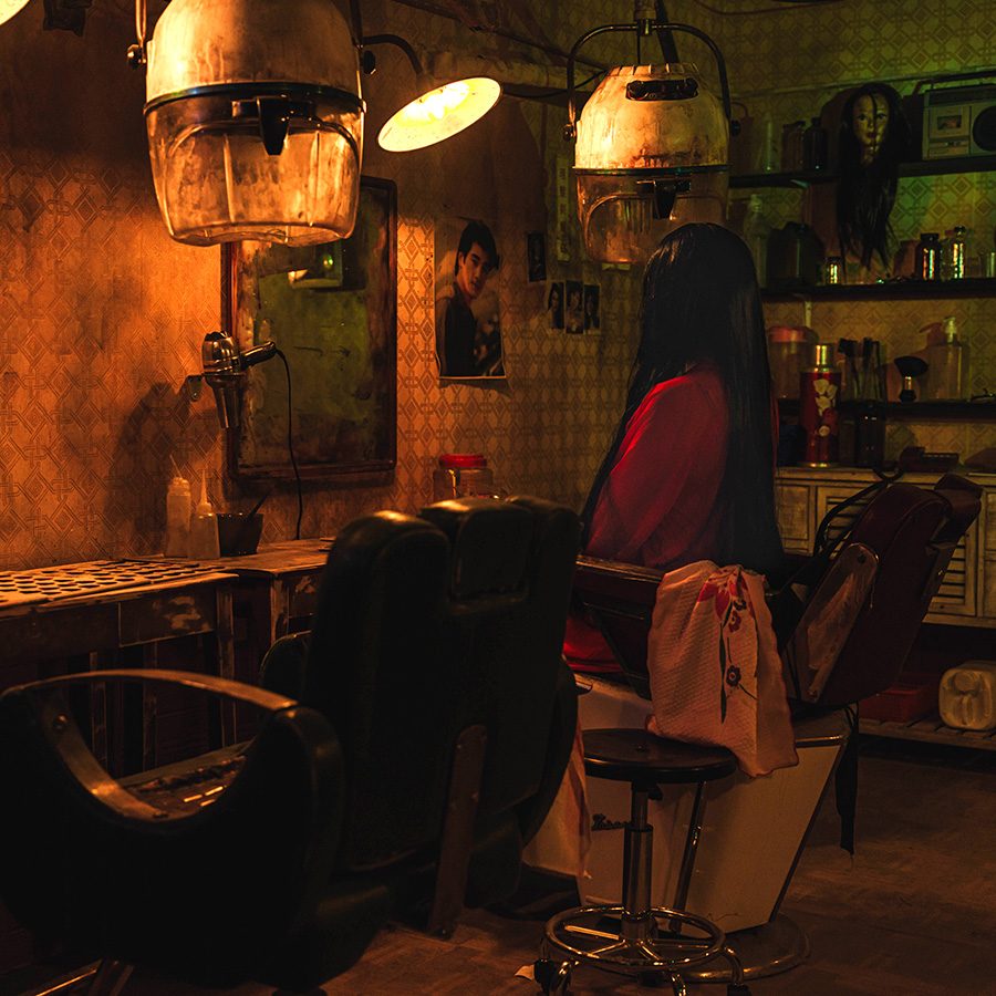 Woman sits alone at an abandoned barber shop at Airside’s Hollow City. 