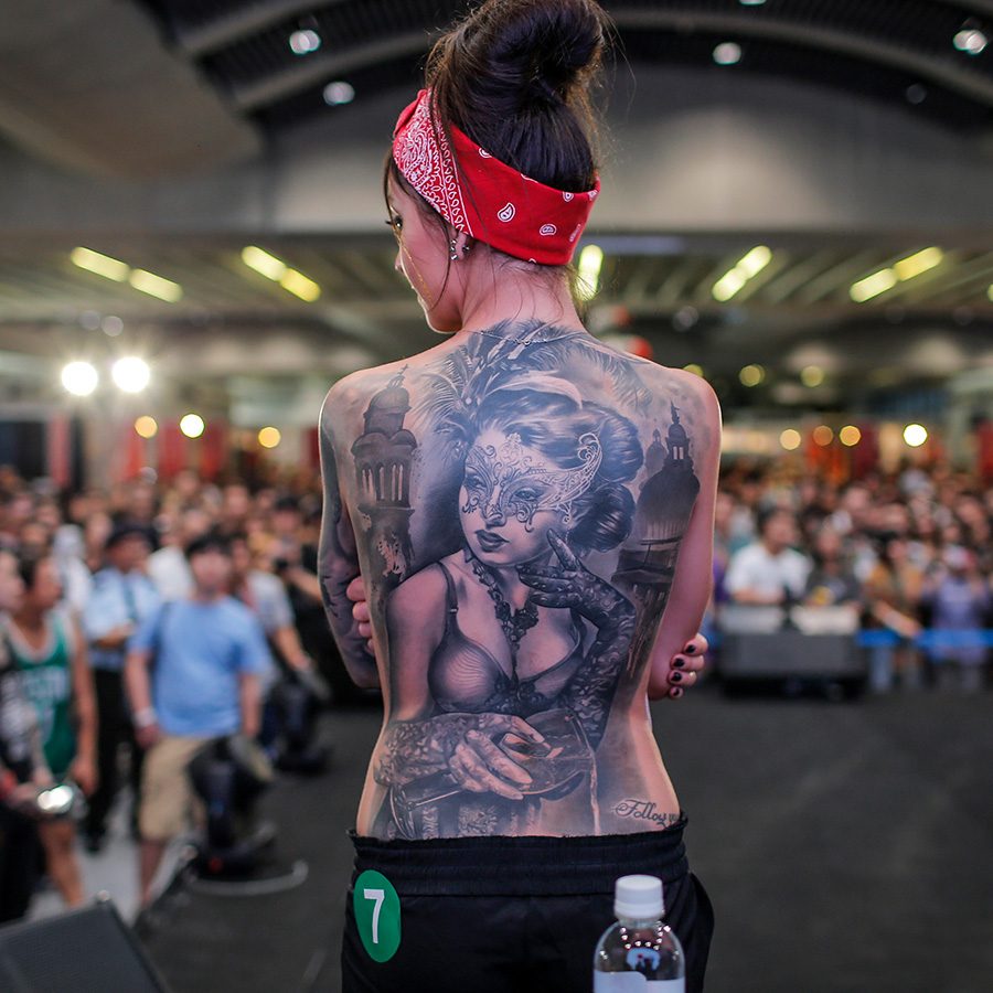 Woman displays a large tattoo on her back.