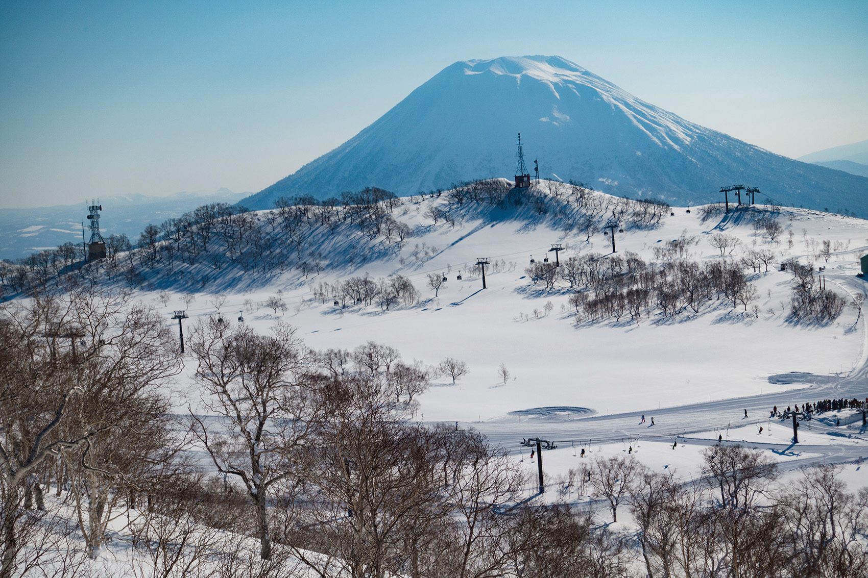 a view of a snowy mountain and people skiing down the slope in Japan