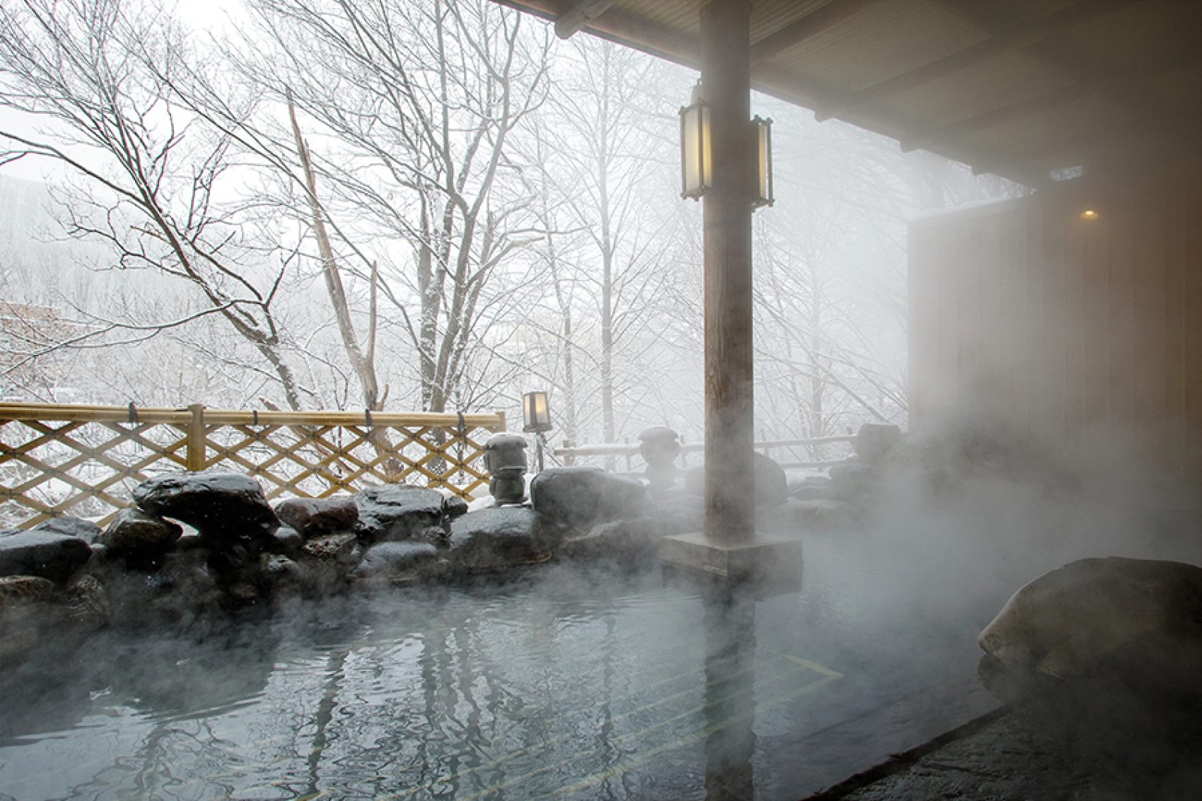 A steaming hot spring with views of snow falling on Shikotsu-Toya National Park in winter at Jozankei Onsen in Sapporo, Hokkaido, Japan