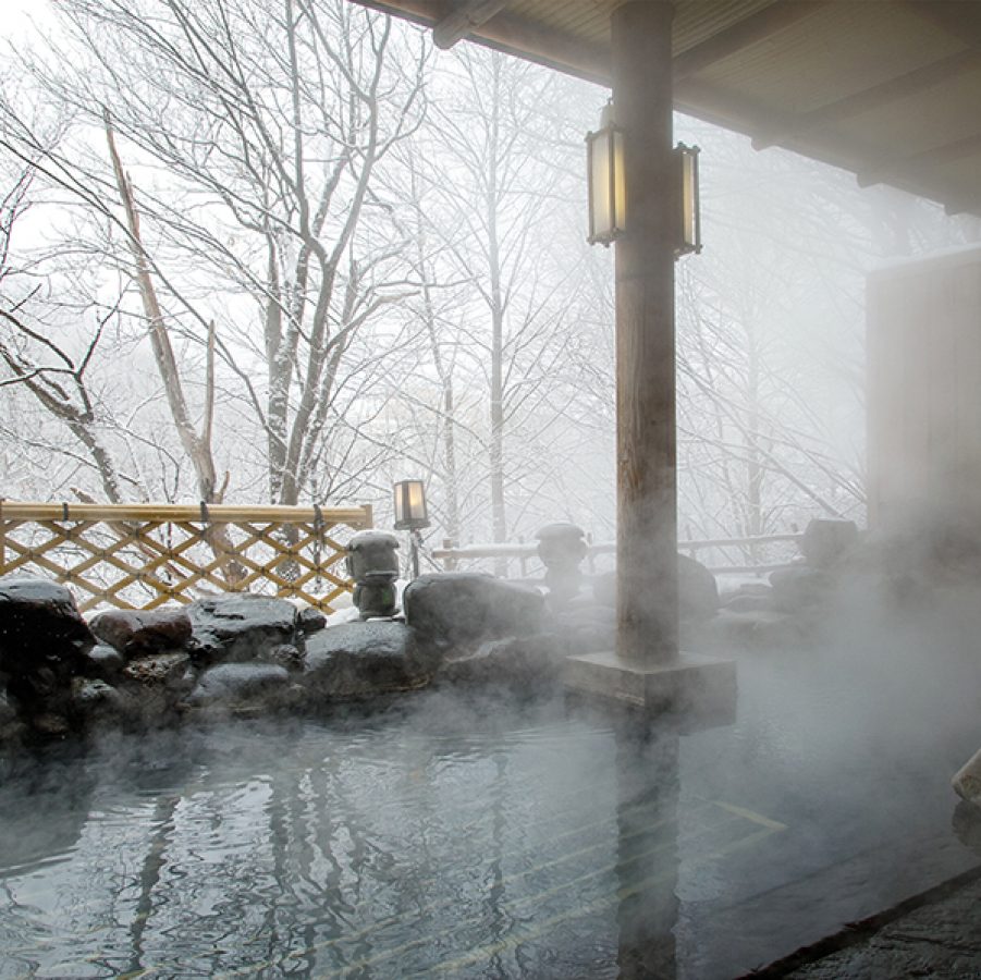 A steaming hot spring with views of snow falling on Shikotsu-Toya National Park in winter at Jozankei Onsen in Sapporo, Hokkaido, Japan