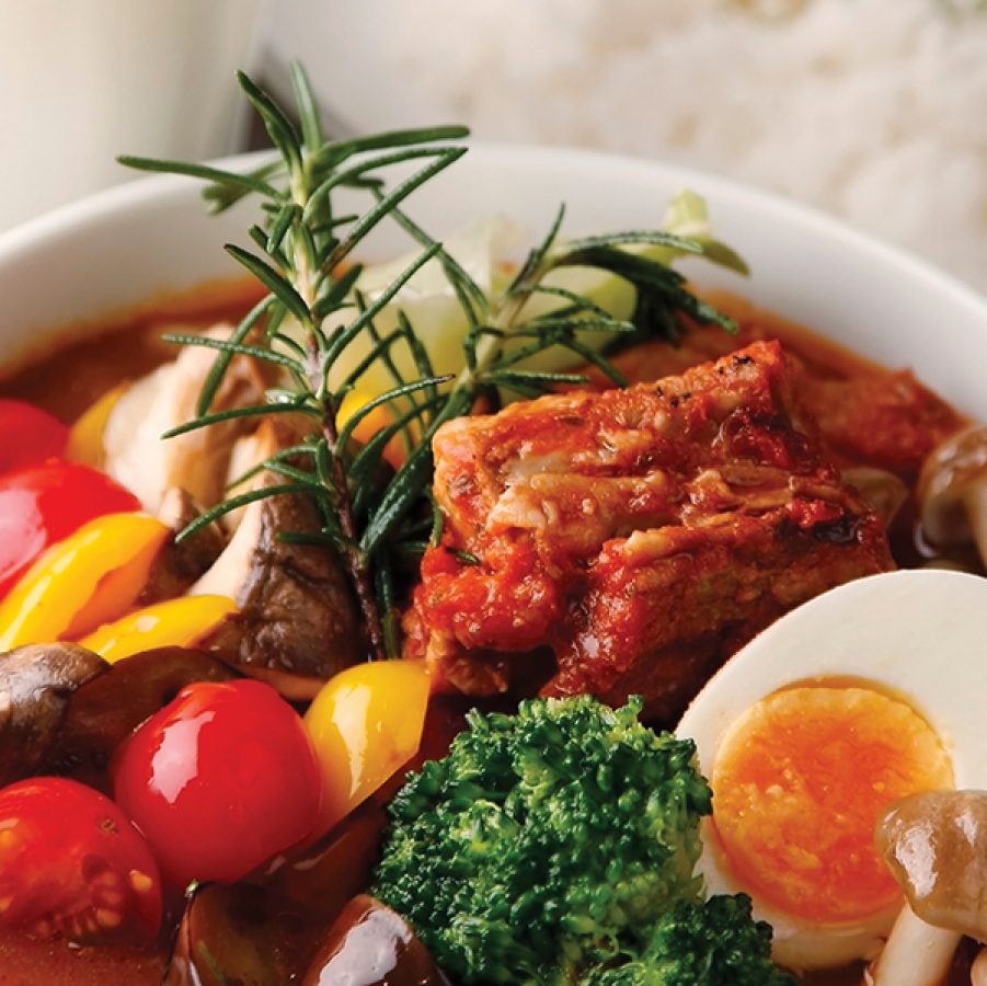 A close-up of a bowl of curry with mushroom, kimchi, tomato, egg and vegetables