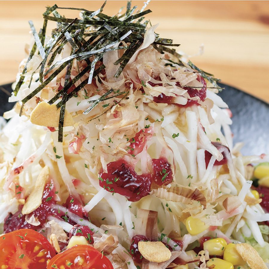 A close-up of a plate of salad garnished with seaweed and corn served at Sumibi Izakaya