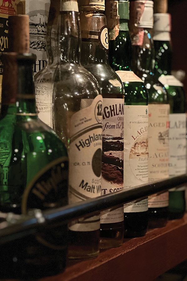 A close-up of a shelf filled with a variety of whisky bottles on display on display at The Bow Bar in Hokkaido, Japan