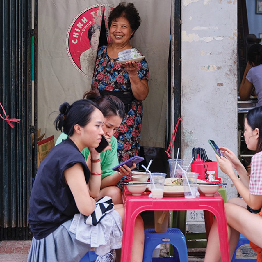 Staff member at Pho Cuon Chinh Thang smiles as she brings out pho cuon to customers