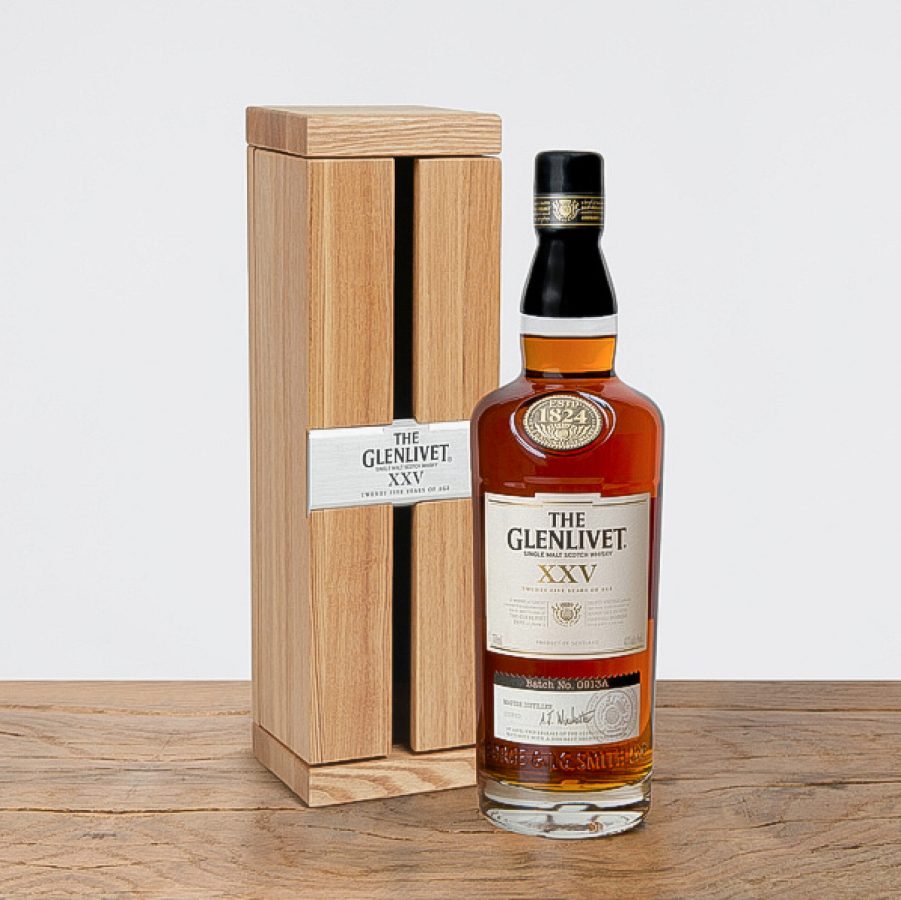 A bottle of The Glenlivet XXV Single Malt Scotch Whisky next to its wooden box. 