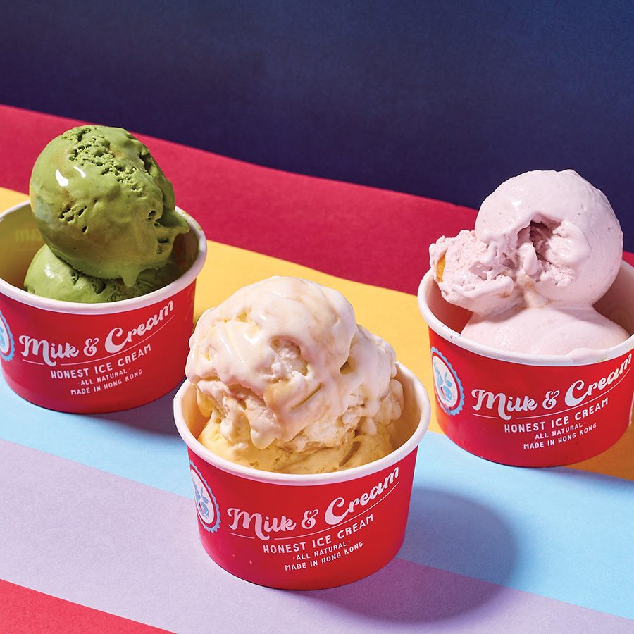 Three red “Milk & Cream” cups with two scoops of ice cream each, placed against a rainbow backdrop. 