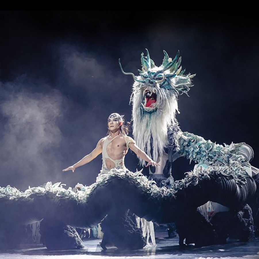  A man standing next to a dragon on stage for Pingtan Impression.
