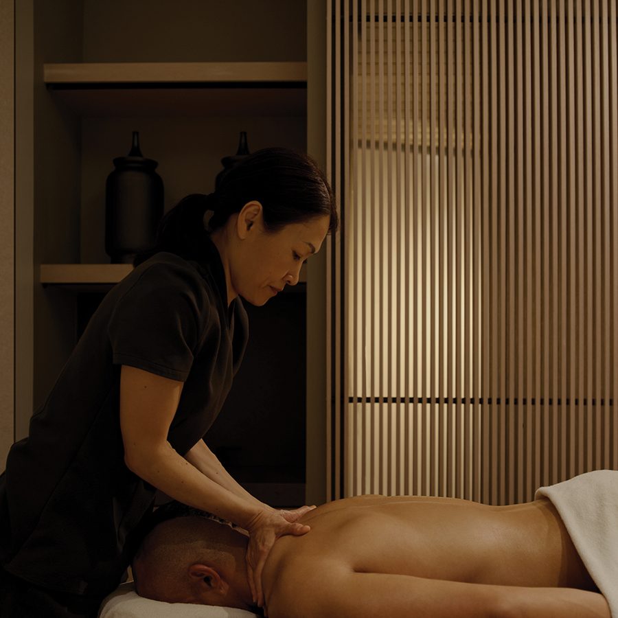 A person lying face-down is given a massage by a massage therapist 