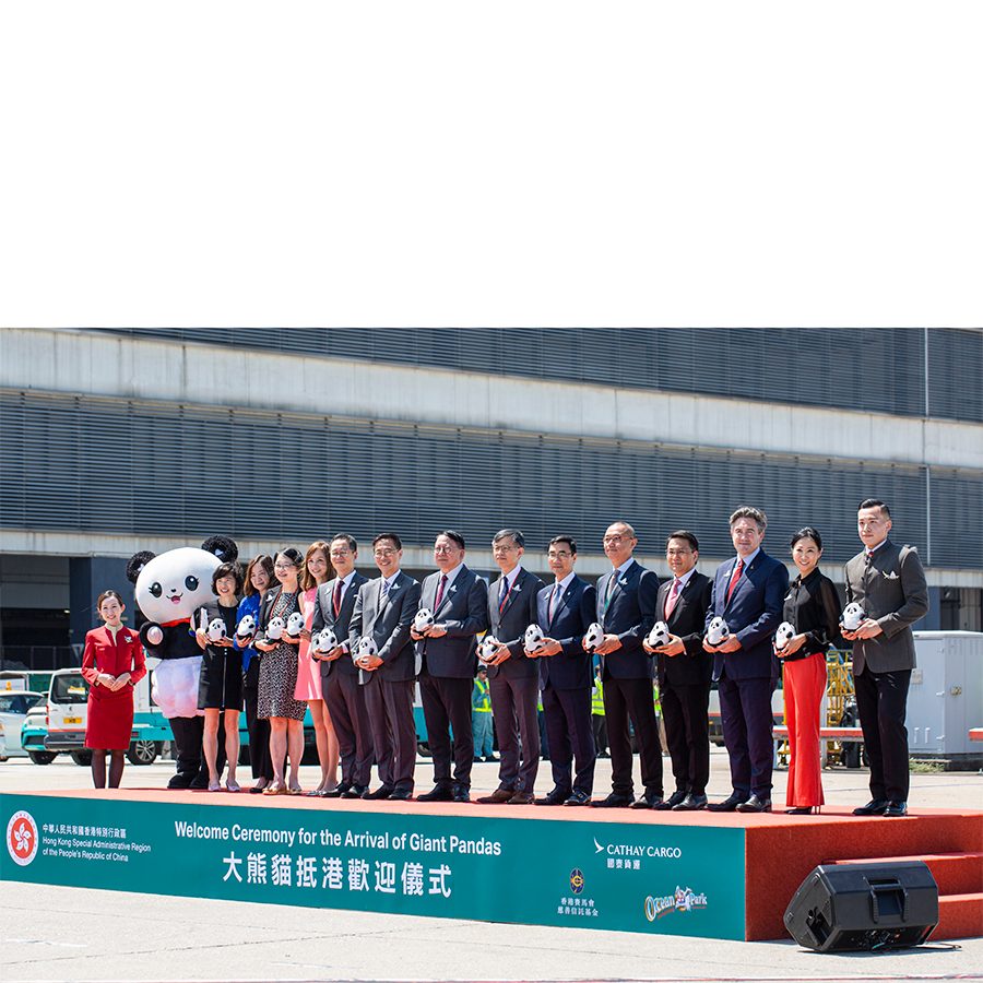 Group stands on a stage alongside a Cathay Pacific flight attendant and panda mascot 
