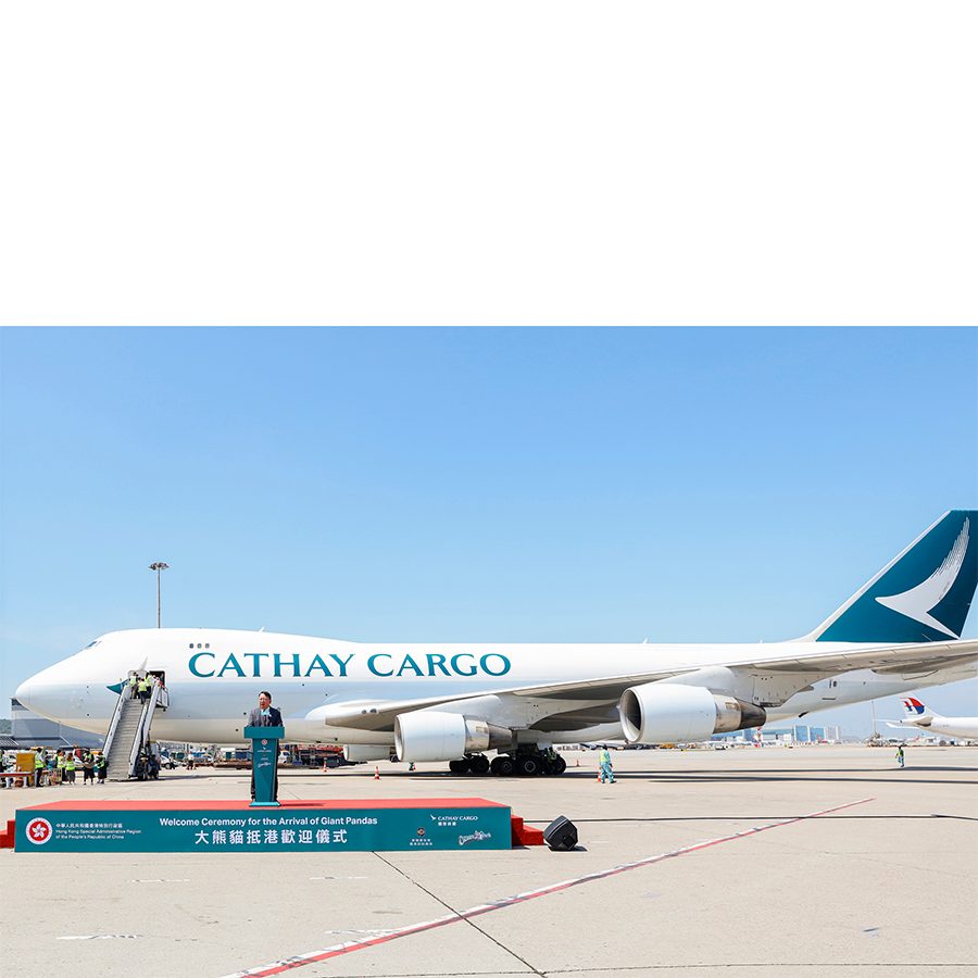 Person stands at a podium in front of a Cathay Cargo plane