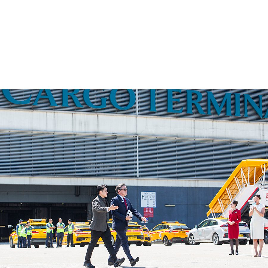 Two people walk along the tarmac at the Cathay Cargo Terminal