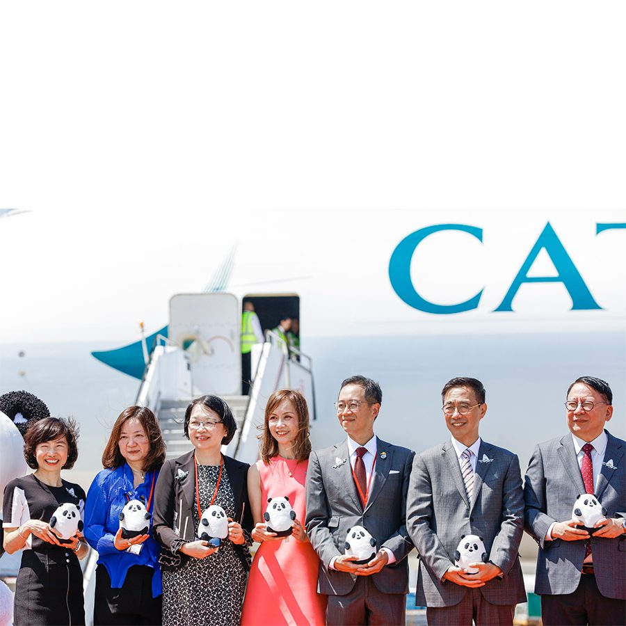 Group stands in front of a Cathay Cargo plane holding panda stuffed toys 