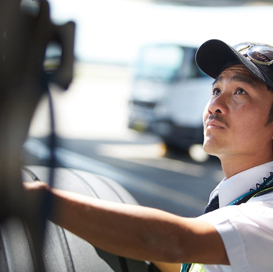 A man wearing a cap and headphones with his hand placed on an airplane tyre.  