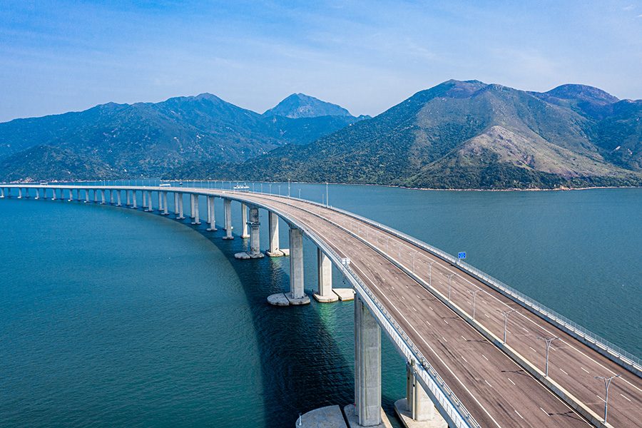 The Hong Kong-Zhuhai-Macao-Bridge from afar with a mountain range in the background. 