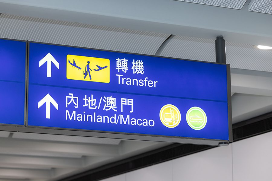 A blue sign showing where to go for transfers to the Chinese mainland and Macao at Hong Kong International Airport.  
