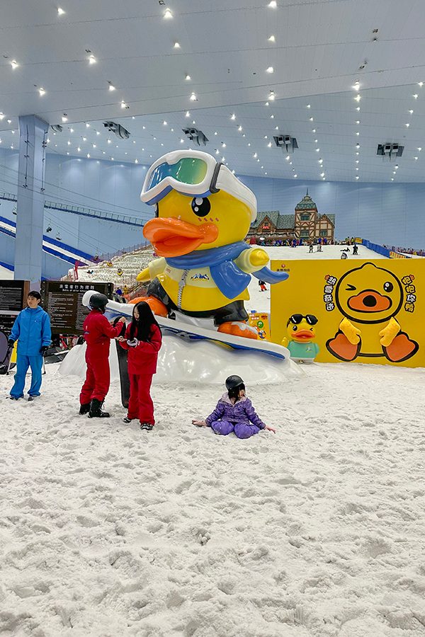 A snow play area that also offers tubing at Guangzhou Sunac Snow Park, decorated with images and a statue of a cartoon duck. 