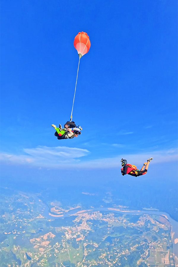 Two groups of skydivers falling from high above Zhaoqing, seen far below. 