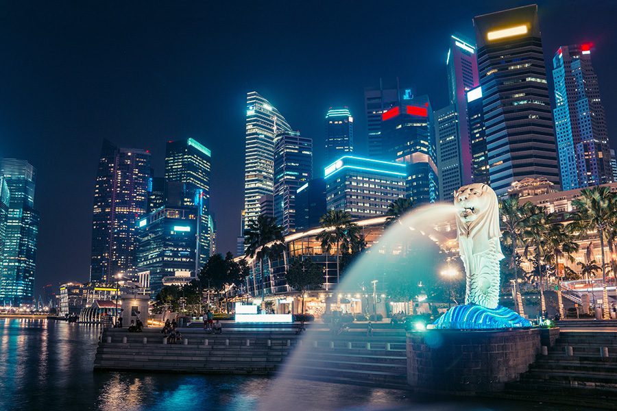 Merlion statue spraying water against backdrop of Singaporean skyline