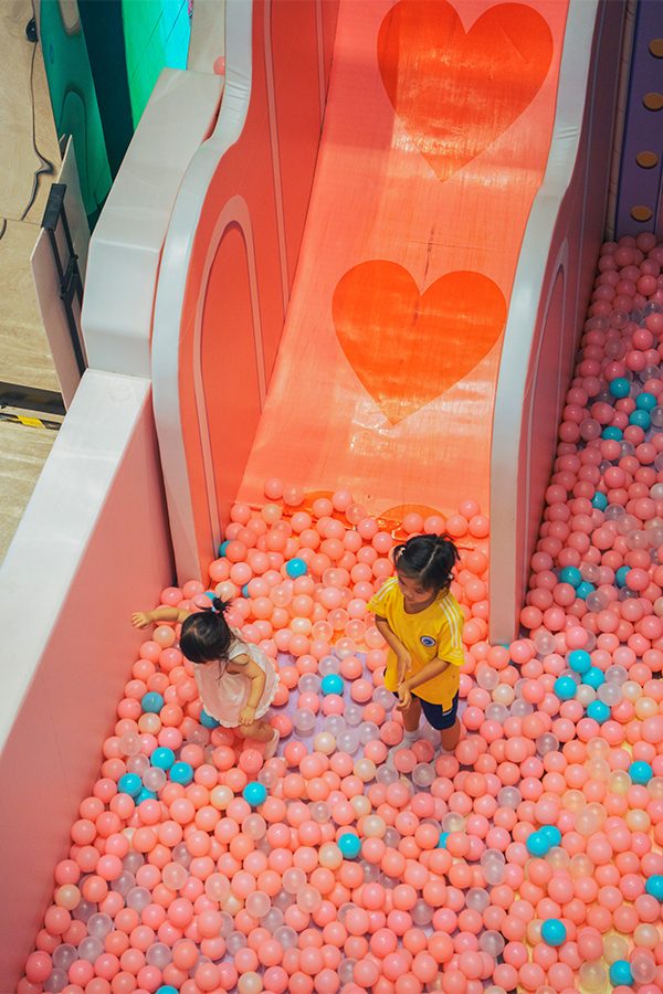 Two toddlers playing in the ball pit beneath the slide in Futian Coco Park’s children’s play zone. 