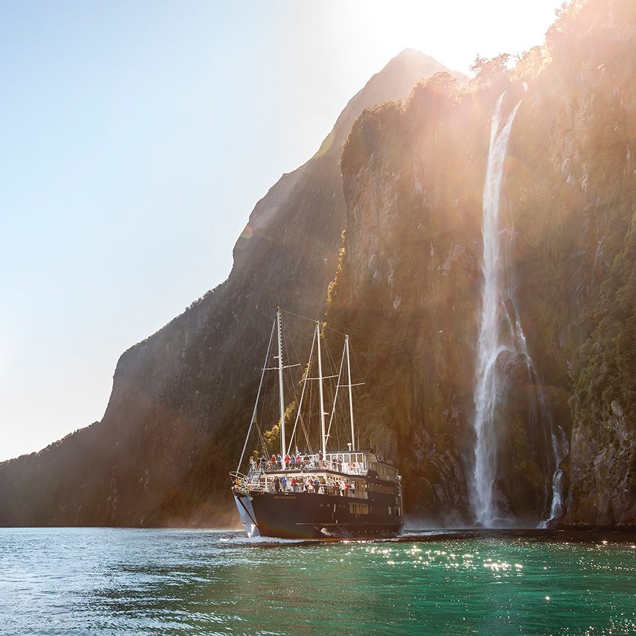 Boat next to a waterfall in Milford Sound