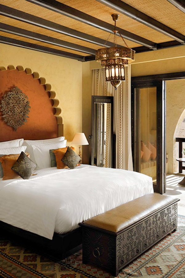The soothing modern interiors of bedroom suite and balcony at Qasr Al Sarab Desert Resort by Anantara in Abu Dhabi, with a view of the expansive desert during daytime 